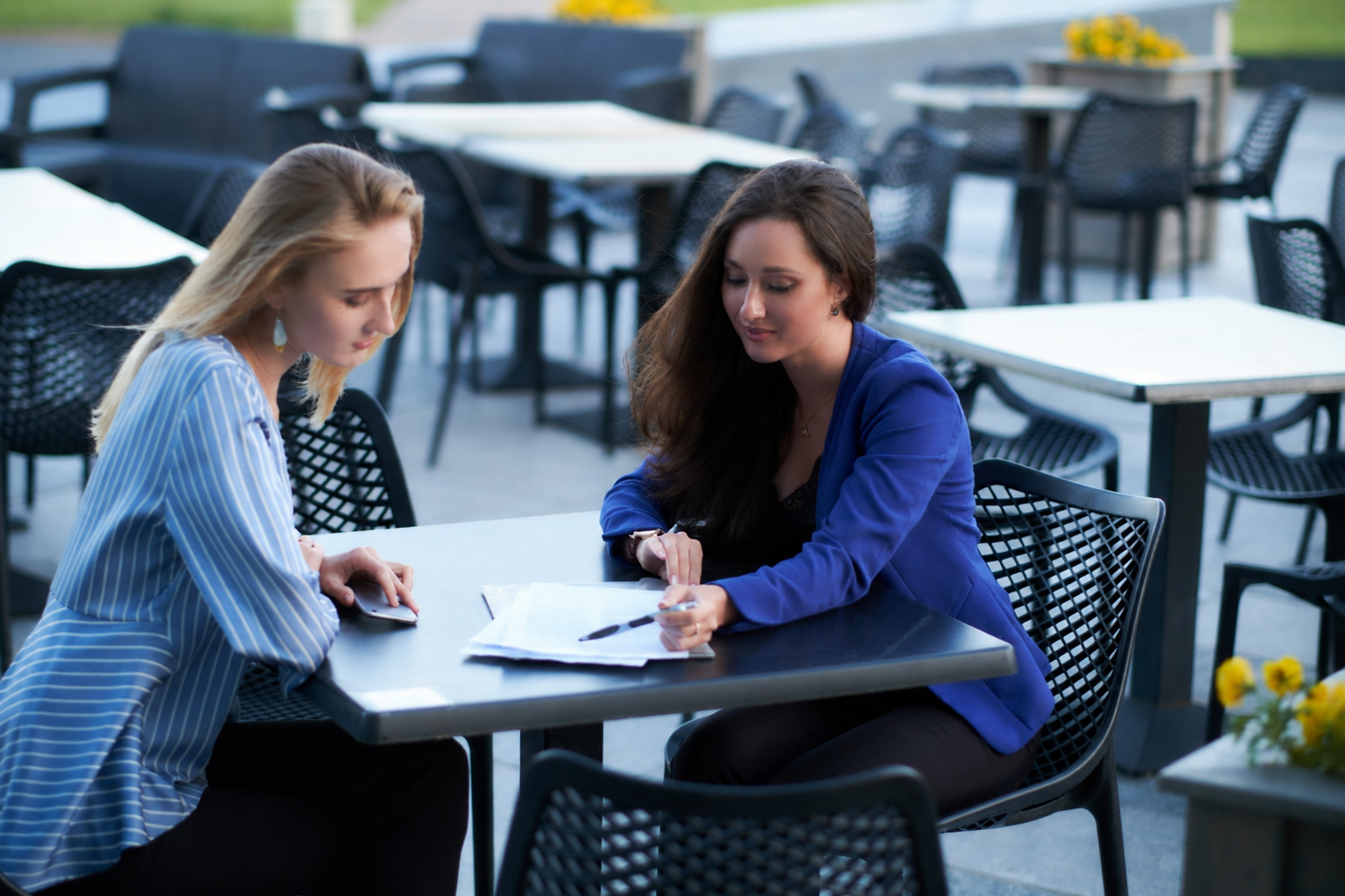 two woman sat at a table looking at documents