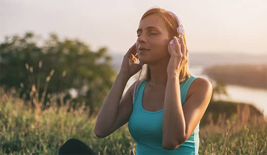 woman sat in field wearing headphones