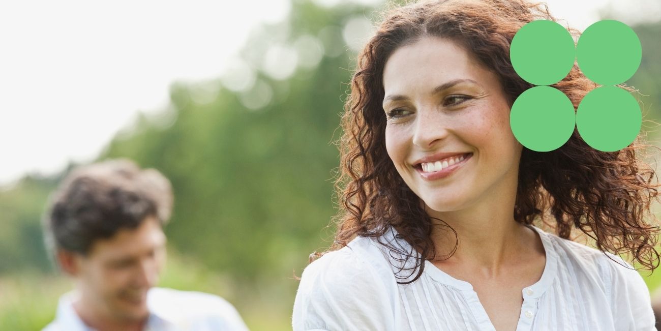 woman wearing white smiling with green icon in top right corner