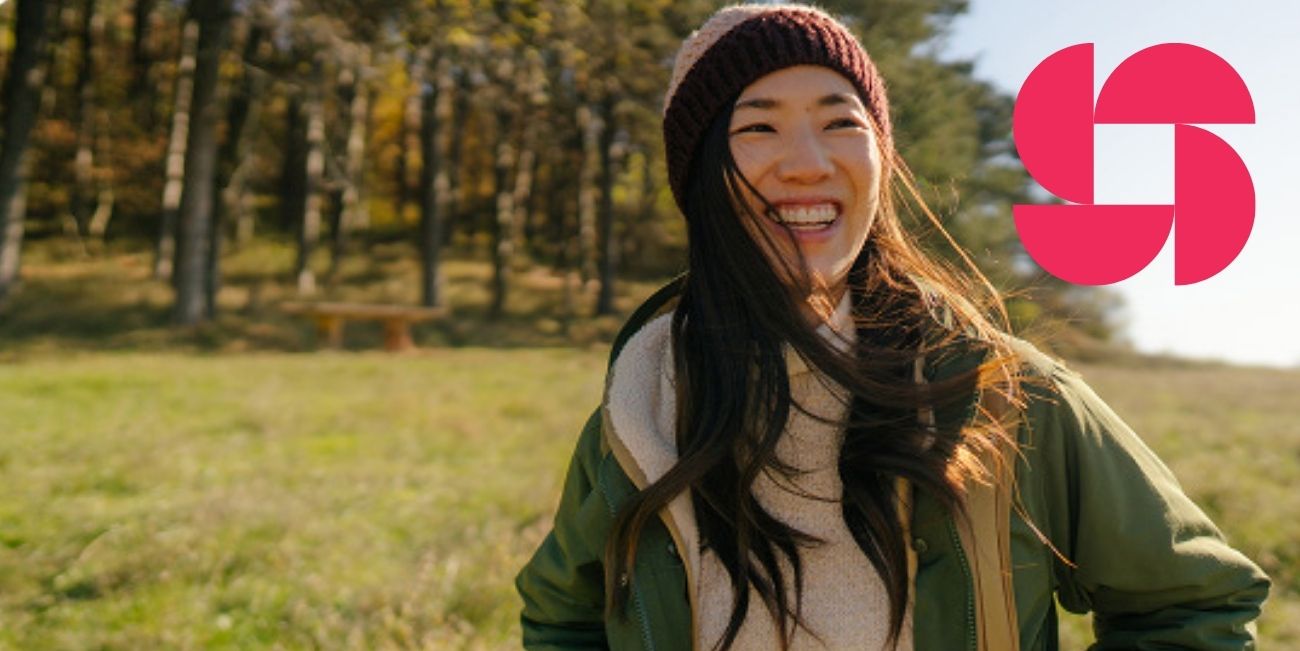 woman walking near forest with pink icon in top right corner